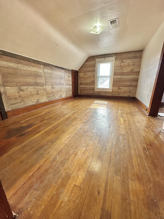 bonus room featuring hardwood / wood-style floors, vaulted ceiling, and wood walls