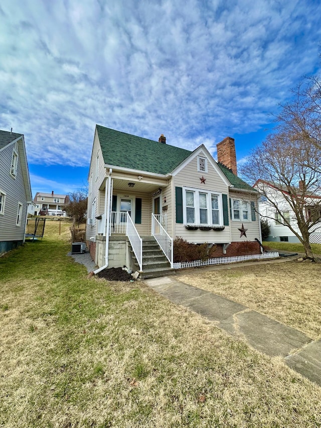 bungalow-style home featuring a porch, a front lawn, and central air condition unit