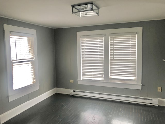 spare room featuring a baseboard radiator, ornamental molding, and dark hardwood / wood-style flooring