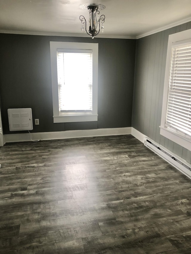 unfurnished room featuring ornamental molding, dark wood-type flooring, heating unit, and an inviting chandelier