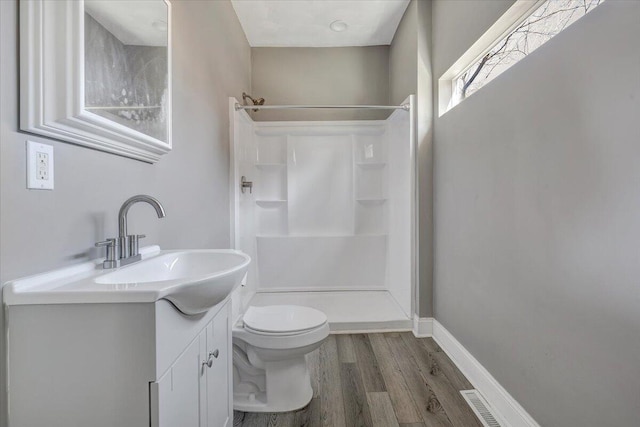 bathroom with vanity, toilet, wood-type flooring, and a shower