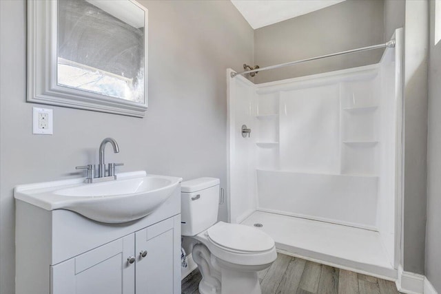 bathroom with hardwood / wood-style flooring, a shower, vanity, and toilet