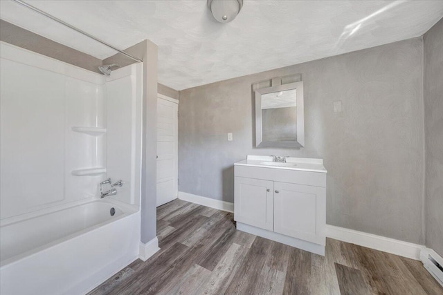 bathroom featuring vanity, hardwood / wood-style flooring, baseboard heating, and shower / bath combination