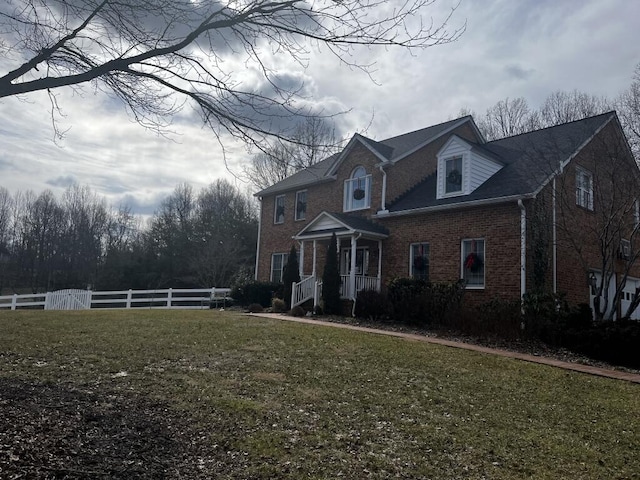 traditional-style house with brick siding, fence, and a front lawn