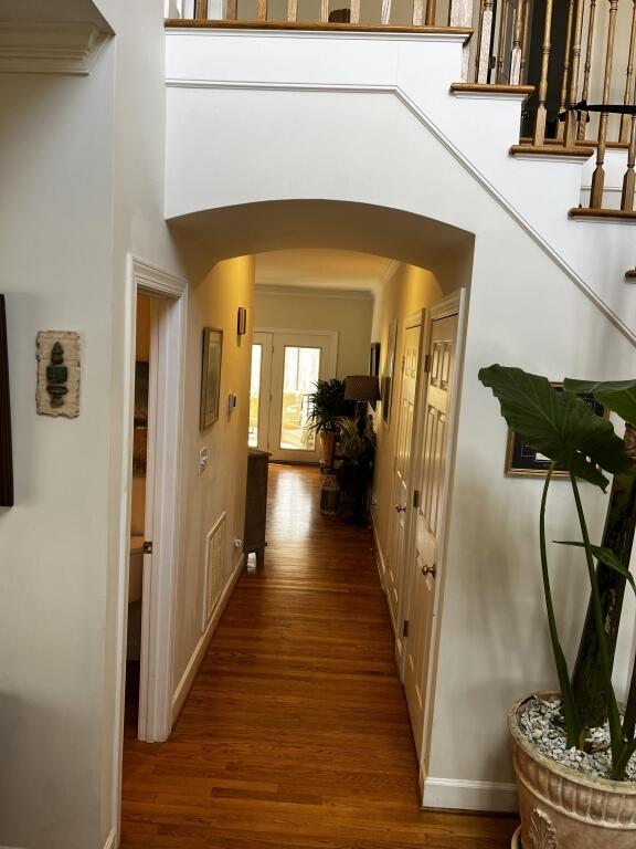 hall featuring stairs, arched walkways, a high ceiling, and wood finished floors