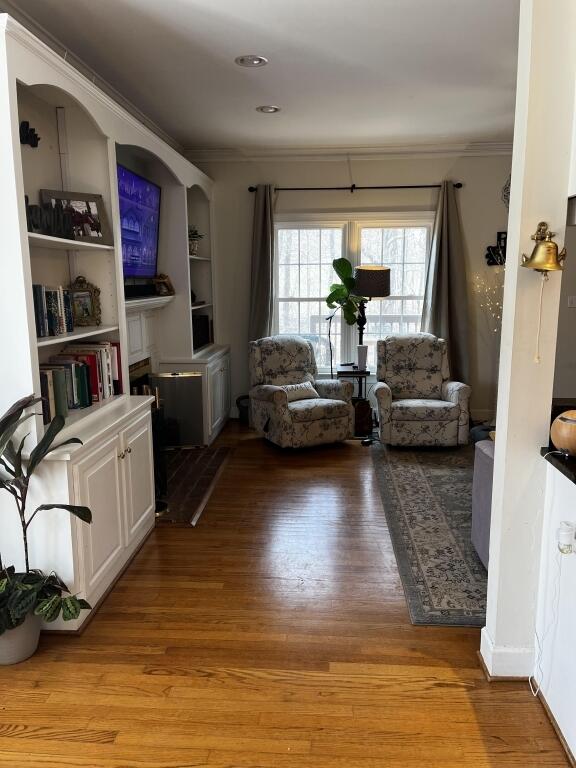 living room featuring light wood-style flooring and crown molding