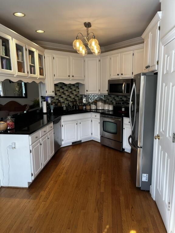 kitchen featuring stainless steel appliances, pendant lighting, white cabinets, and glass insert cabinets