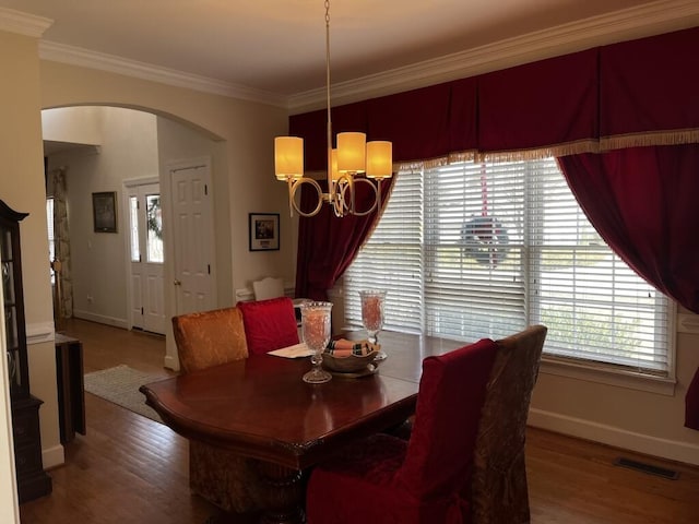 dining room with arched walkways, visible vents, crown molding, and wood finished floors