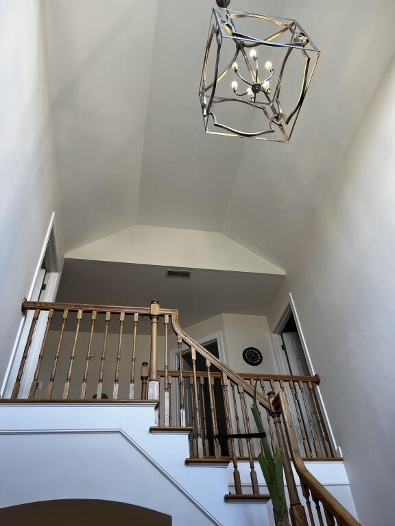 stairway featuring lofted ceiling and a notable chandelier