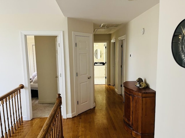 corridor featuring visible vents, an upstairs landing, baseboards, dark wood finished floors, and attic access