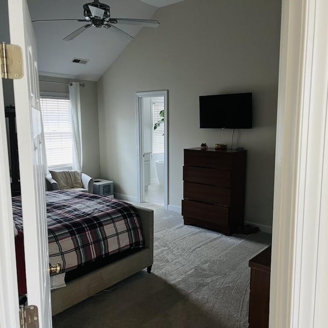 bedroom with dark colored carpet, lofted ceiling, visible vents, ensuite bathroom, and baseboards