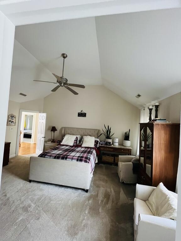 bedroom featuring carpet floors, lofted ceiling, visible vents, and a ceiling fan