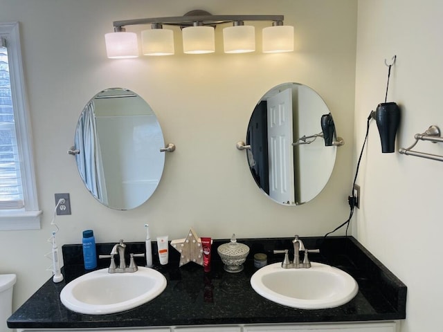 bathroom featuring double vanity, toilet, and a sink