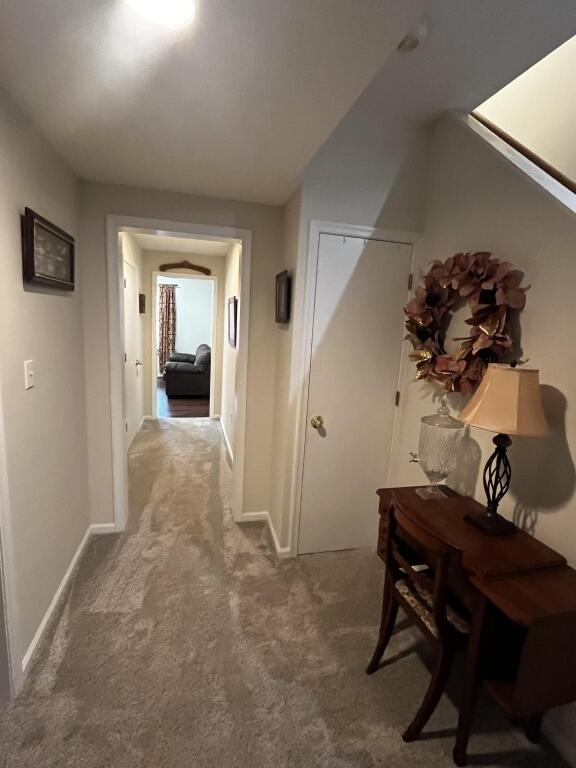 hallway with carpet floors and baseboards