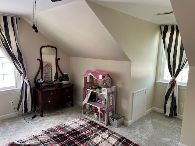 interior space with a healthy amount of sunlight, vaulted ceiling, and light carpet