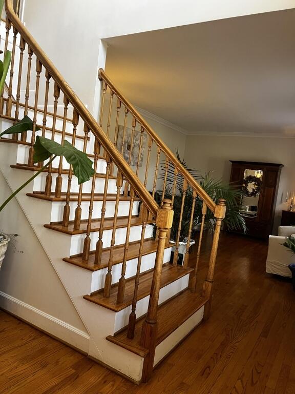 stairs featuring ornamental molding, wood finished floors, and baseboards