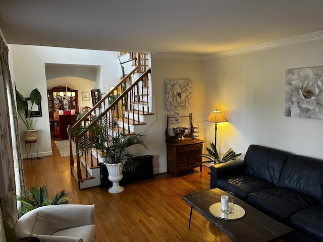 living room with baseboards, arched walkways, stairway, wood finished floors, and crown molding