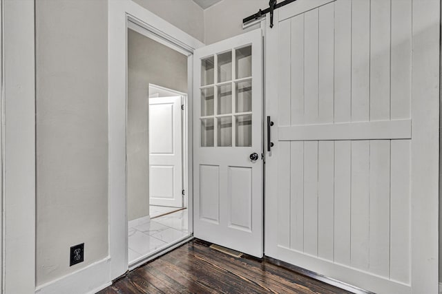 entryway with a barn door and dark hardwood / wood-style floors