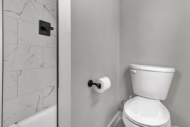 bathroom featuring a tile shower and toilet