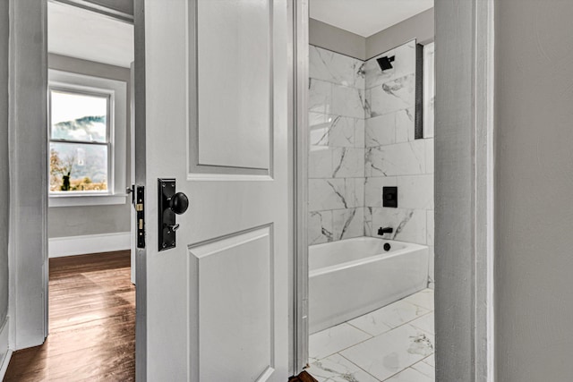 bathroom with hardwood / wood-style floors and tiled shower / bath