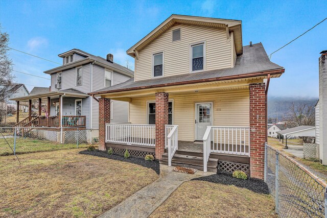 view of front facade featuring fence private yard, covered porch, and a front yard