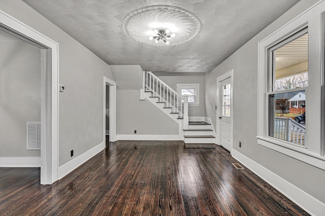 foyer entrance with visible vents, baseboards, wood finished floors, and stairs