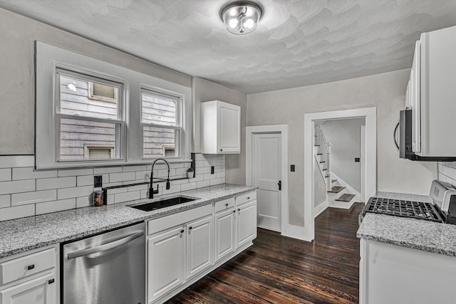 kitchen with appliances with stainless steel finishes, sink, white cabinets, light stone countertops, and dark wood-type flooring