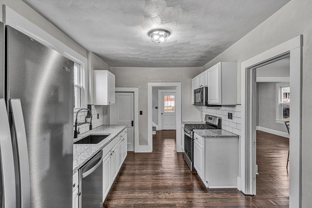 kitchen featuring white cabinetry, light stone countertops, appliances with stainless steel finishes, and sink