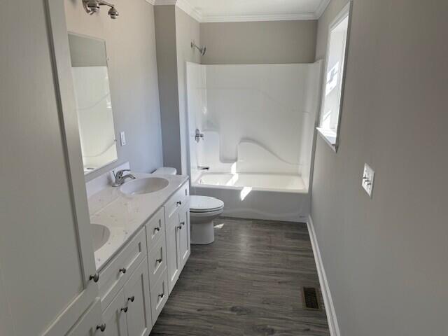 bathroom with visible vents, bathing tub / shower combination, a sink, crown molding, and toilet