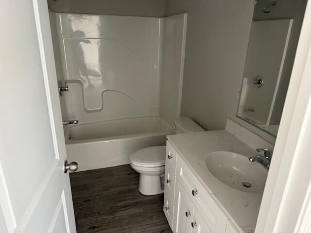 bathroom featuring vanity, toilet, wood finished floors, and  shower combination