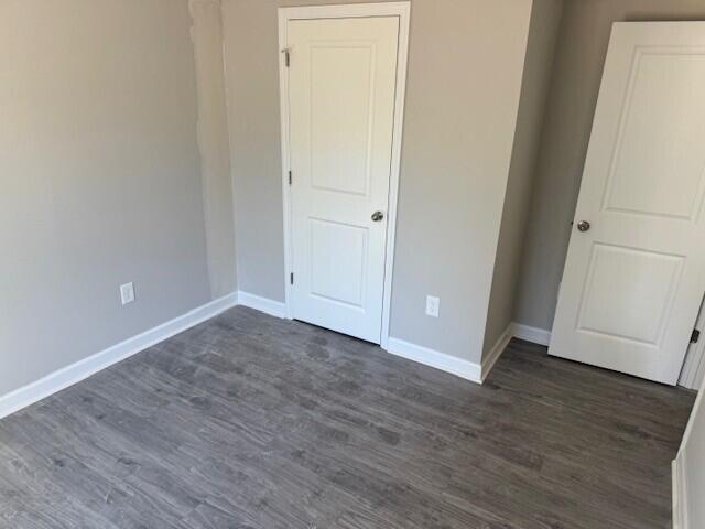 unfurnished room with dark wood-style floors, baseboards, and crown molding