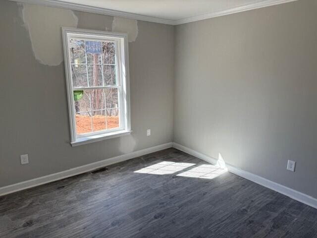 empty room featuring dark wood finished floors, baseboards, and ornamental molding