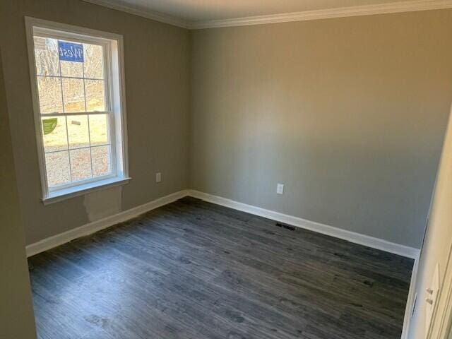 empty room featuring dark wood finished floors, crown molding, and baseboards