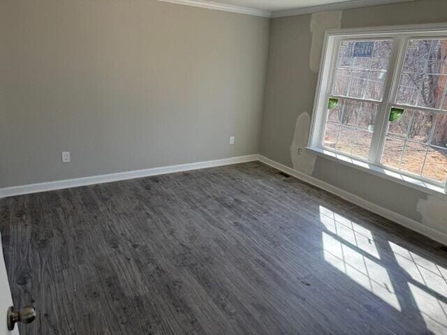 empty room featuring dark wood-style floors, ornamental molding, and baseboards