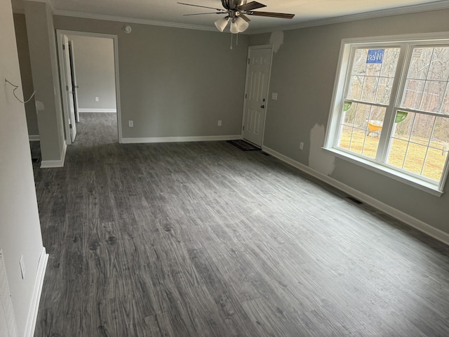 spare room featuring dark wood-style floors, crown molding, and baseboards