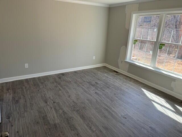 empty room with baseboards, ornamental molding, and dark wood-style flooring