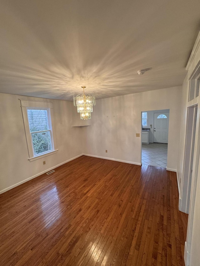 spare room with dark wood-type flooring and a chandelier