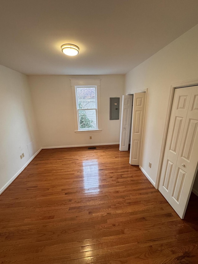 spare room with electric panel and dark hardwood / wood-style flooring