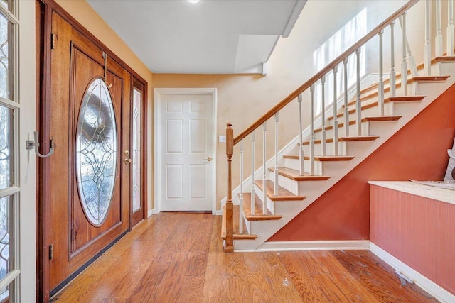 foyer featuring stairs, light wood finished floors, and baseboards