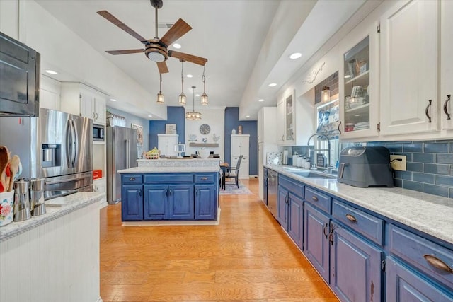 kitchen featuring appliances with stainless steel finishes, blue cabinetry, sink, and white cabinets