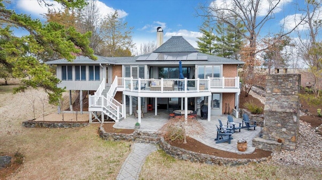 rear view of property with a patio area, a deck, stairs, and brick siding