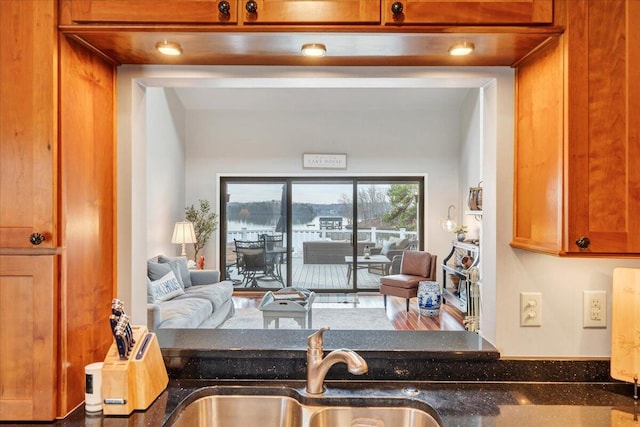 kitchen featuring a sink, dark stone counters, and brown cabinetry