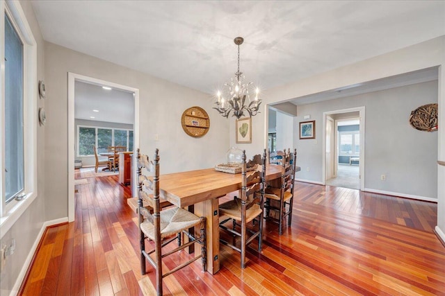 dining room featuring baseboards, plenty of natural light, a notable chandelier, and hardwood / wood-style floors