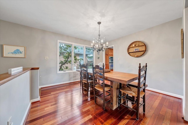 dining area with hardwood / wood-style flooring, a notable chandelier, and baseboards