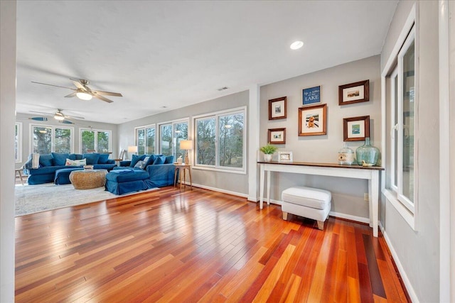 living area featuring visible vents, baseboards, ceiling fan, and hardwood / wood-style floors