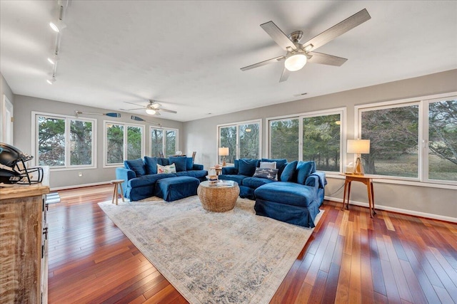 living area featuring baseboards, wood-type flooring, ceiling fan, and rail lighting