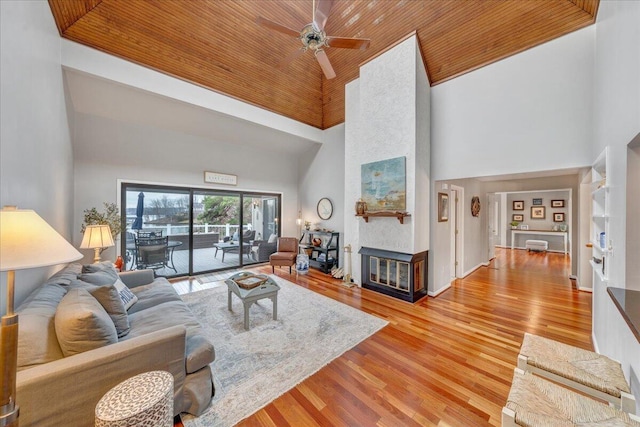 living area featuring ceiling fan, a multi sided fireplace, wooden ceiling, and light wood finished floors