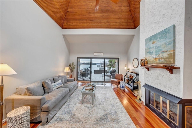 living room with wooden ceiling, high vaulted ceiling, a fireplace, and wood finished floors