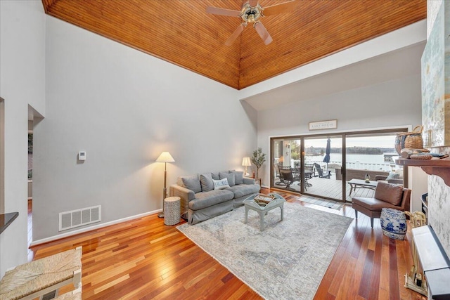 living room with hardwood / wood-style floors, visible vents, a high ceiling, and ceiling fan