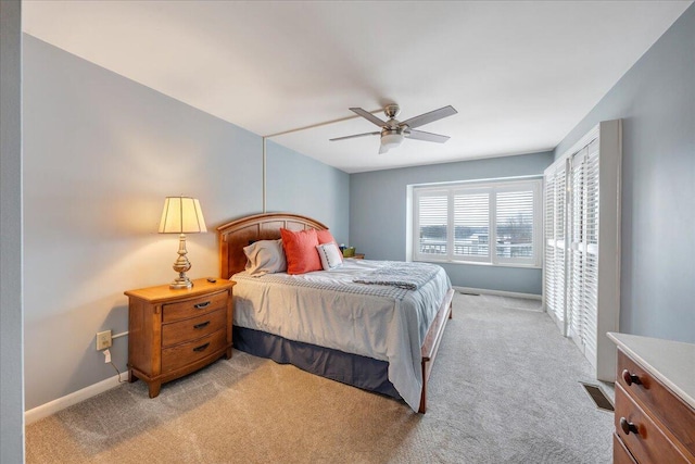 bedroom with baseboards, light carpet, visible vents, and a ceiling fan